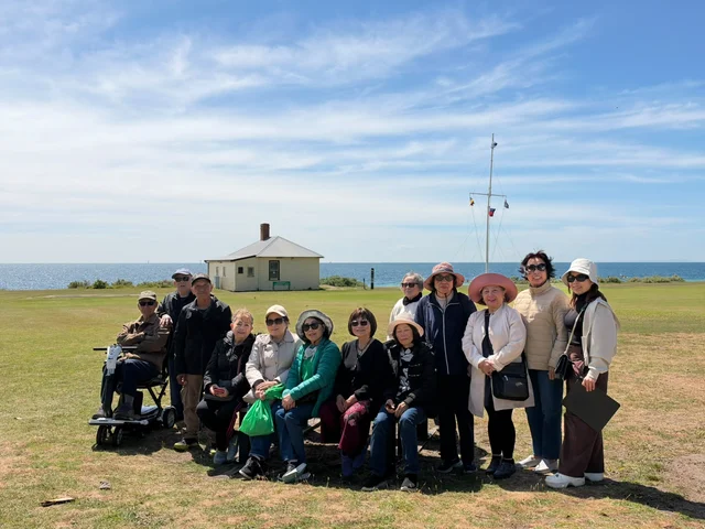 Community members gathering for a photograph on the grass beside the water