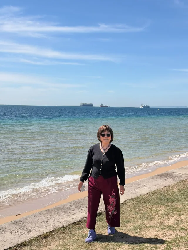 An outing participant standing on the beach beside the calm water