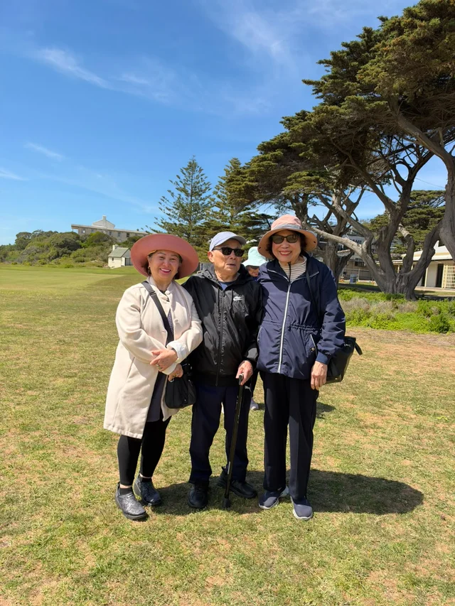 Three community members standing together on the grass on a sunny day