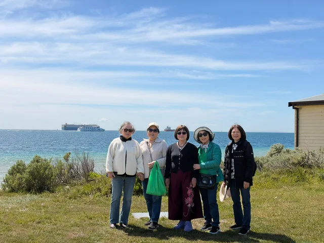 Five community members posing together with the sea behind them